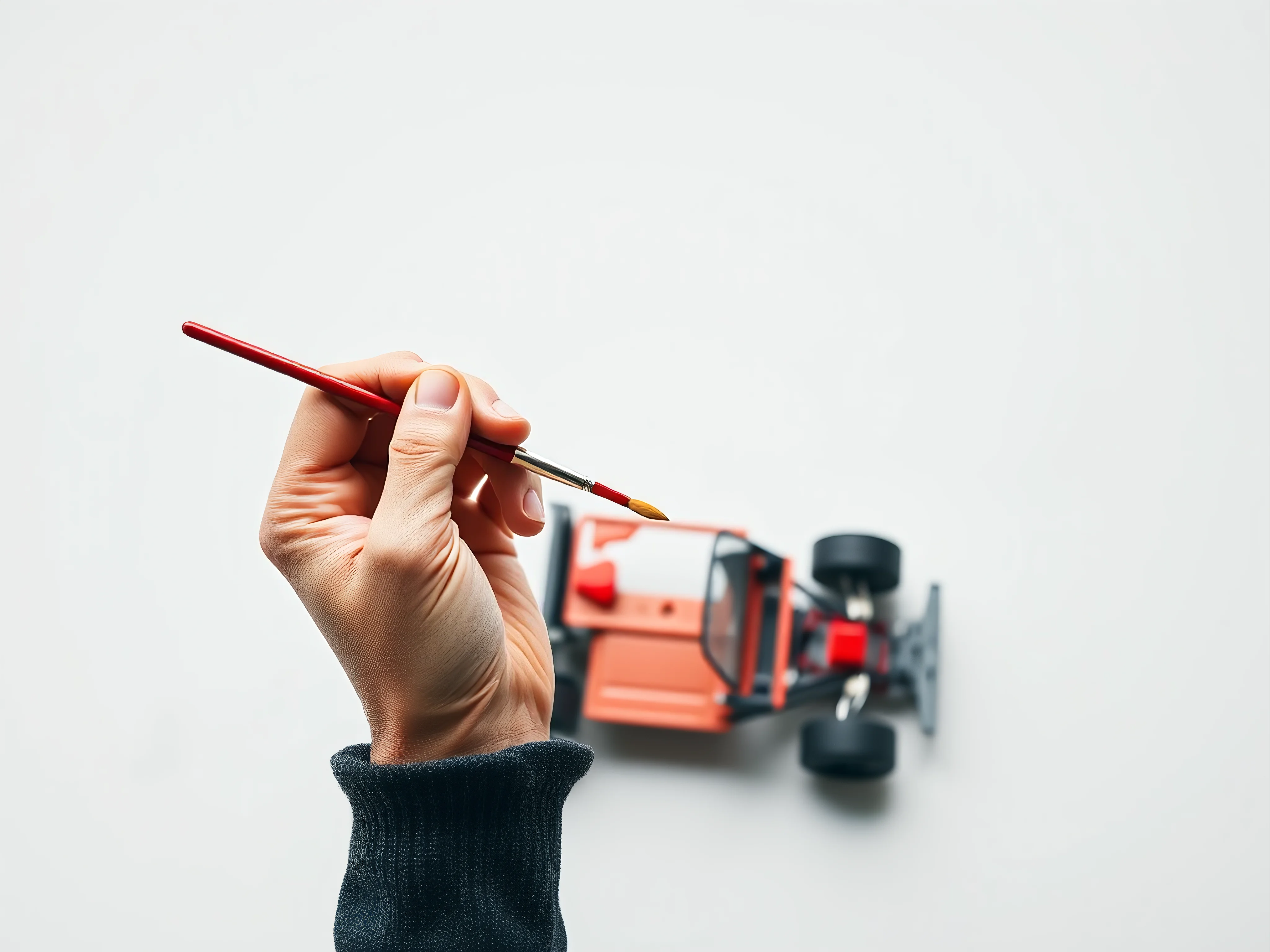 Hand painting a model car with red paint.